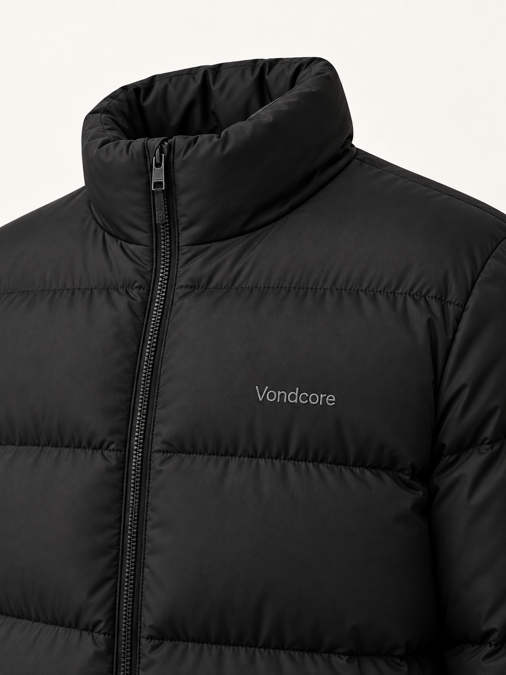 Close detail of the black Vondcore Summit Puffer Jacket showing the stand collar, zipper, quilting and chest embroidery.