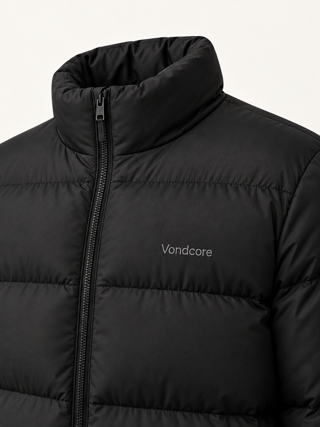 Close detail of the black Vondcore Summit Puffer Jacket showing the stand collar, zipper, quilting and chest embroidery.